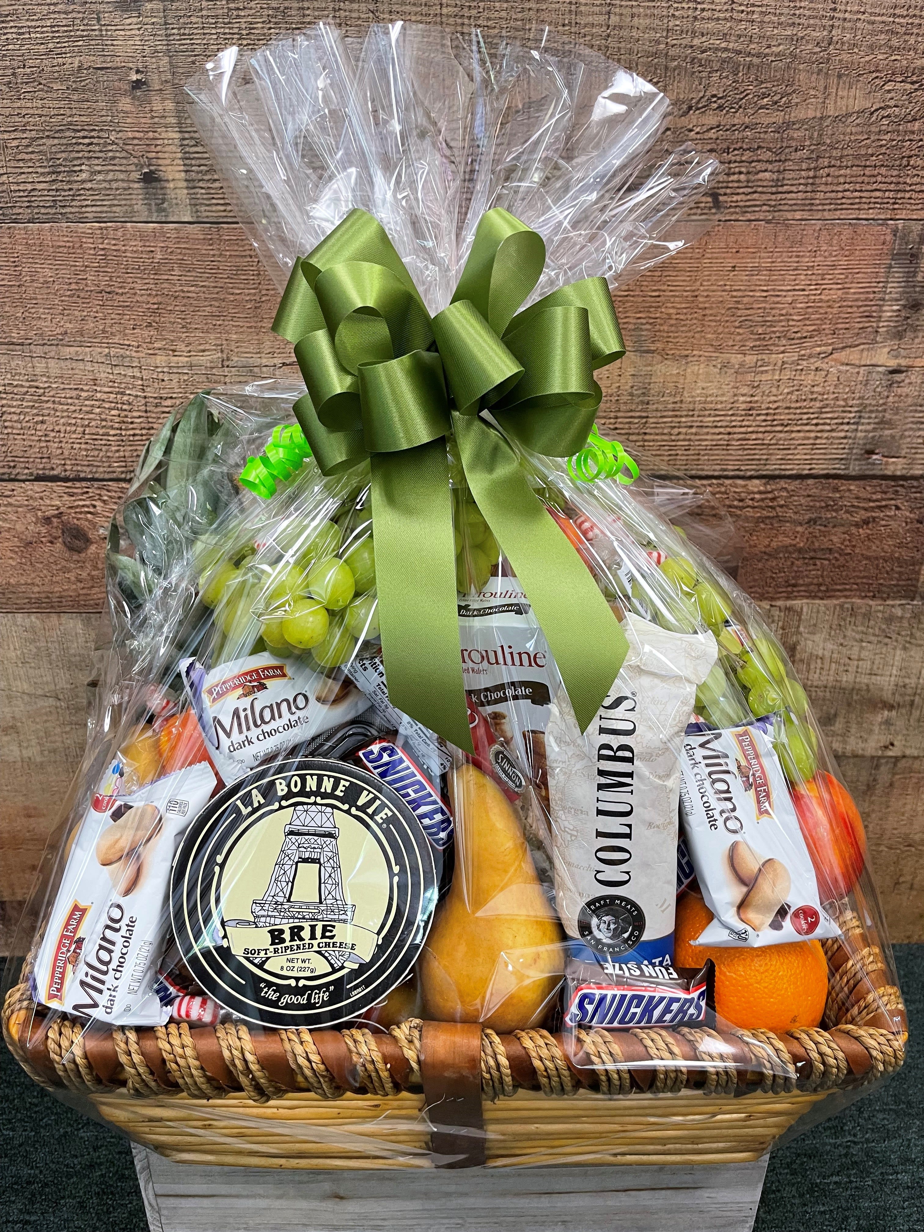 Gift basket with chocolates, cheese, fruit, and snacks wrapped in clear cellophane