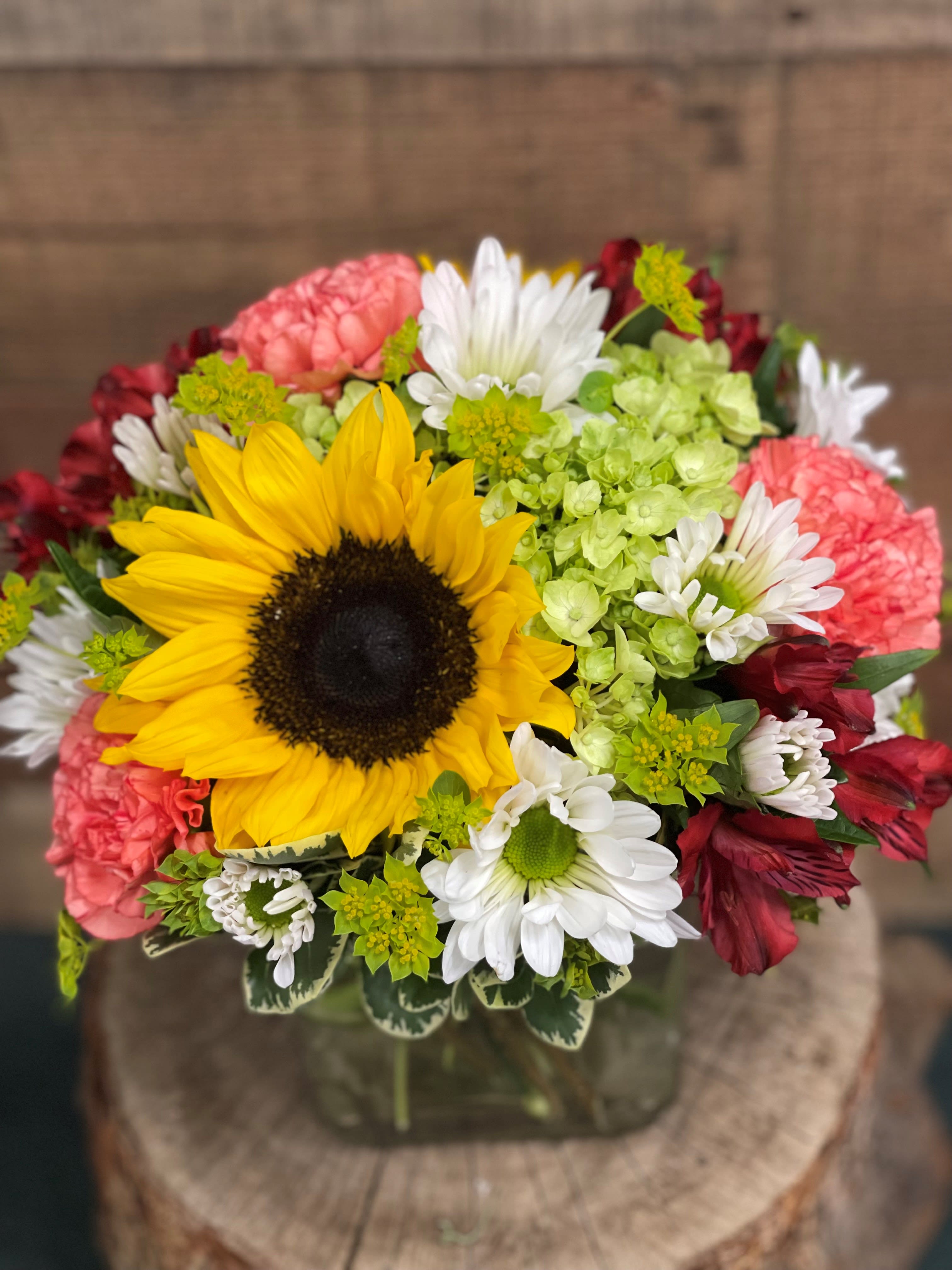 Sunny Days - Sunny sunflowers artfully paired with bright and summery long lasting flowers. Nestled in a square vase, it is the perfect addition to any table.