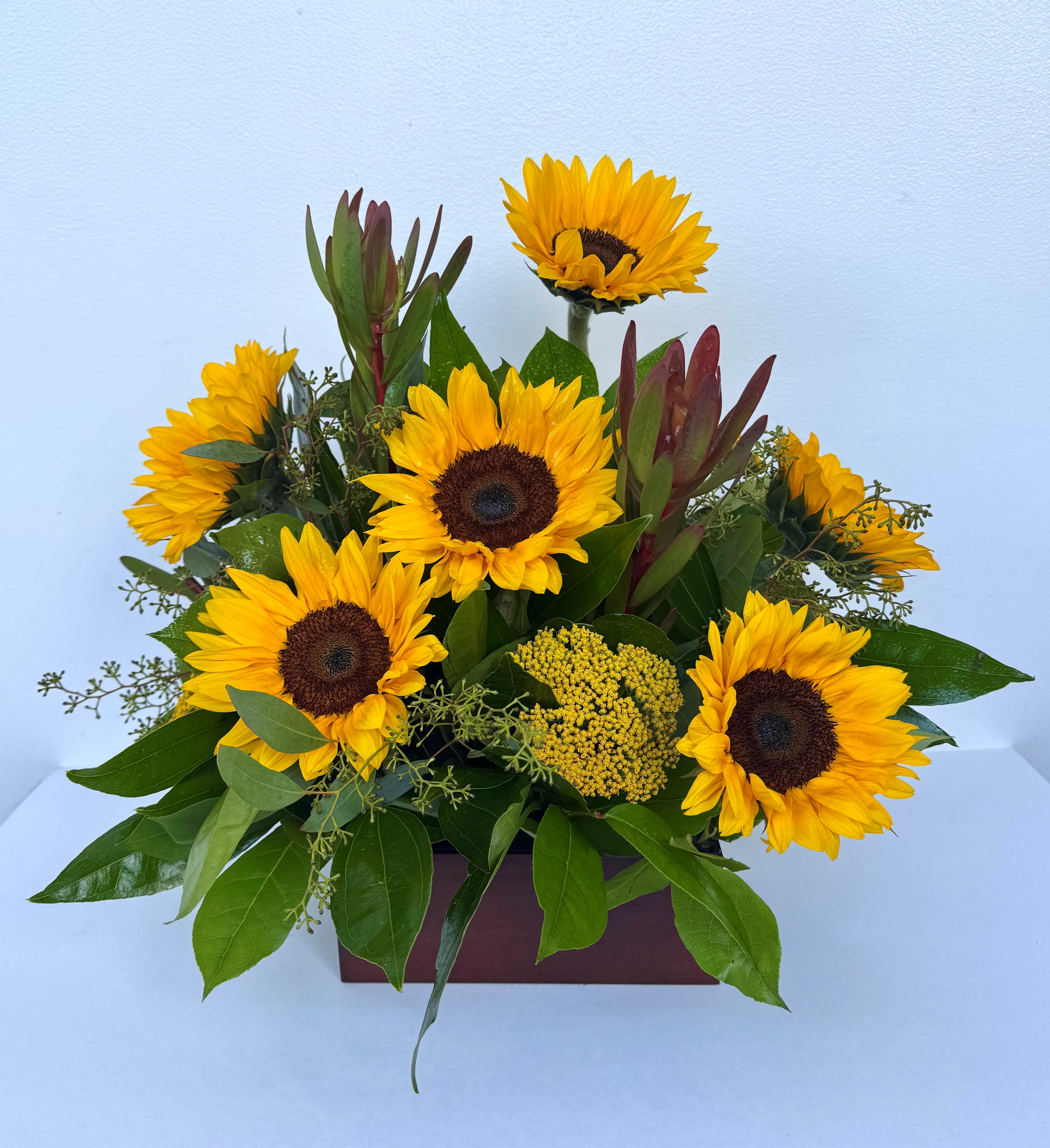 Simply Golden - Rise and shine! Send this beautiful golden bouquet of bright-as-day sunflowers. It's the perfect gift for the light of your life. Bold, bright sunflowers are arranged with delicate greenery, yarrow, Leucadendron and delivered in a Bamboo box.