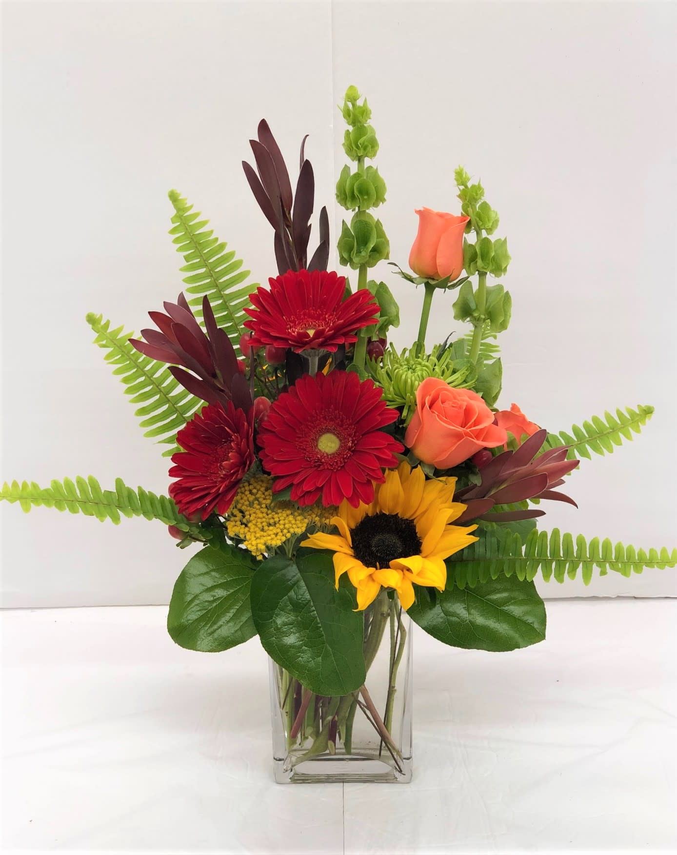 Mixed bouquet in a clear glass vase with red, orange, and yellow blooms