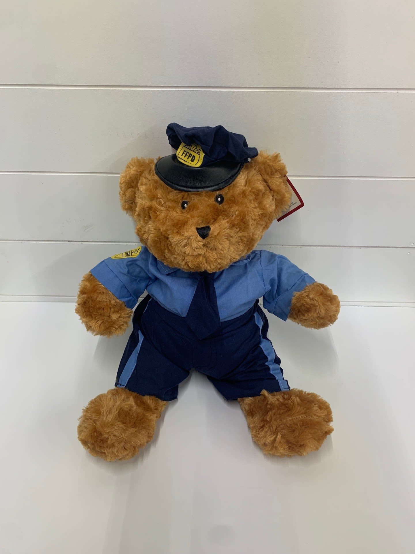 Teddy bear dressed in a blue firefighter uniform and hat