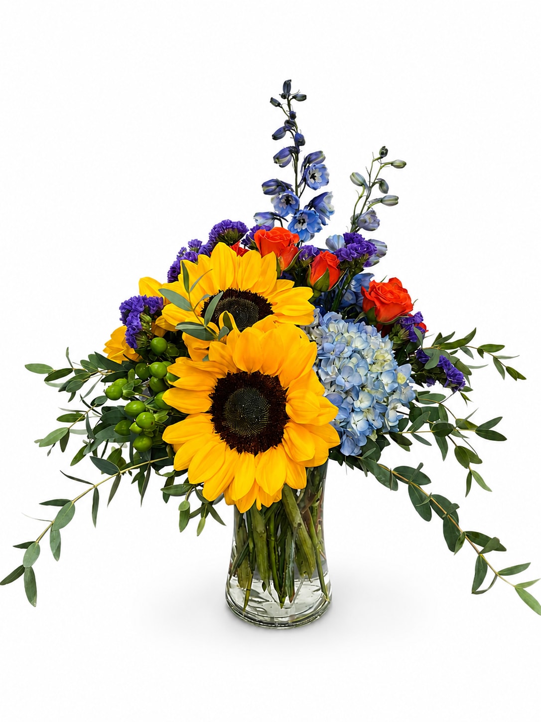Bouquet of sunflowers, blue hydrangea, orange roses, and purple flowers in a glass vase