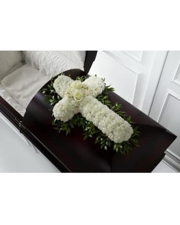 White floral cross arrangement on a dark casket