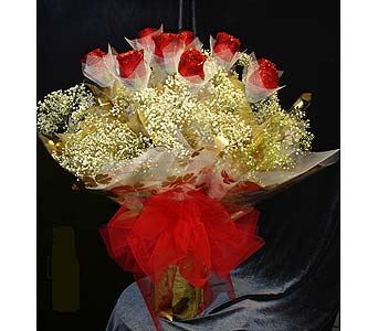 Bouquet of red roses wrapped in white mesh with a red bow