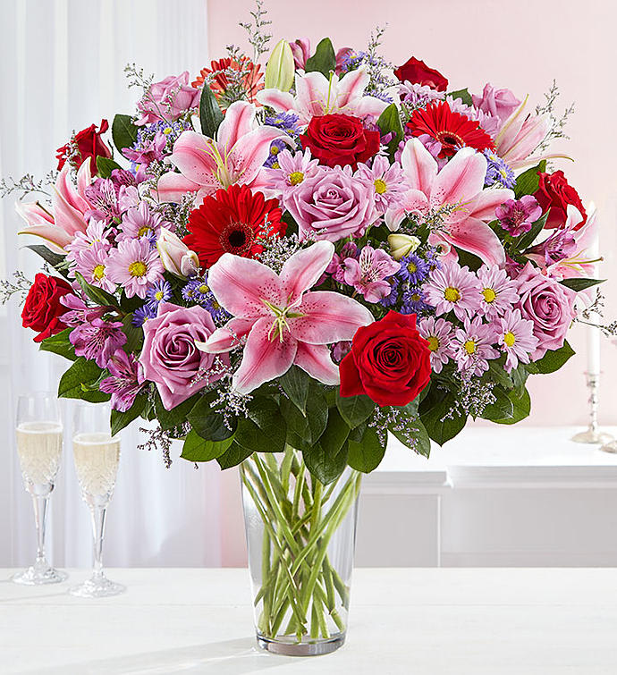 Adoring Love Bouquet™ - For the one you adore above all else, here’s a surprise designed to wow! Our spectacular arrangement is filled with an abundance of lush blooms in soft &amp; bold shades for an exciting contrast of color. Artistically hand-designed by our expert florists, it’s a beautiful gift that expresses the depths of your love.  All-around arrangement with red and lavender roses; pink Oriental lilies; red Gerbera daisies; purple Peruvian lilies (alstroemeria), accented with assorted greenery  To ensure lasting beauty, Oriental lilies and Peruvian lilies may arrive in bud form, and will fully bloom over the next few days  Our florists select the freshest flowers available, so colors and varieties may vary due to local availability  Artistically designed in a clear glass vase; measures 12"H  Arrangement measures approximately 30"H x 22"L