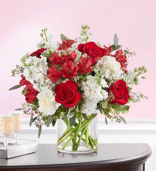 Crimson Rose™ Bouquet - A classic gift for the people and moments worth celebrating. Rich red and pristine white blooms are hand-gathered with lush greenery. A clear glass cylinder vase holds this beautiful surprise, which brings your deepest sentiments to light. All-around arrangement with red roses and Peruvian lilies (alstroemeria); white carnations, stock and waxflower; accented with assorted greenery Artistically designed a clear glass cylinder vase. Arrangement measures approximately 13"H x 12"W