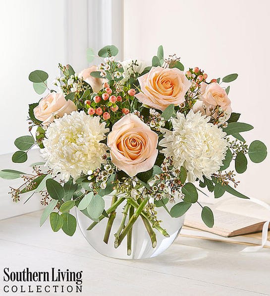 Peach roses and white mums in a clear glass vase