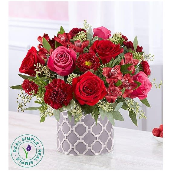 Red and pink rose bouquet in a patterned gray vase