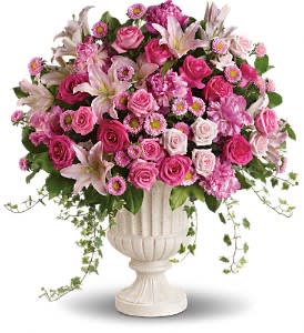 Pink mixed flower arrangement in a white urn vase