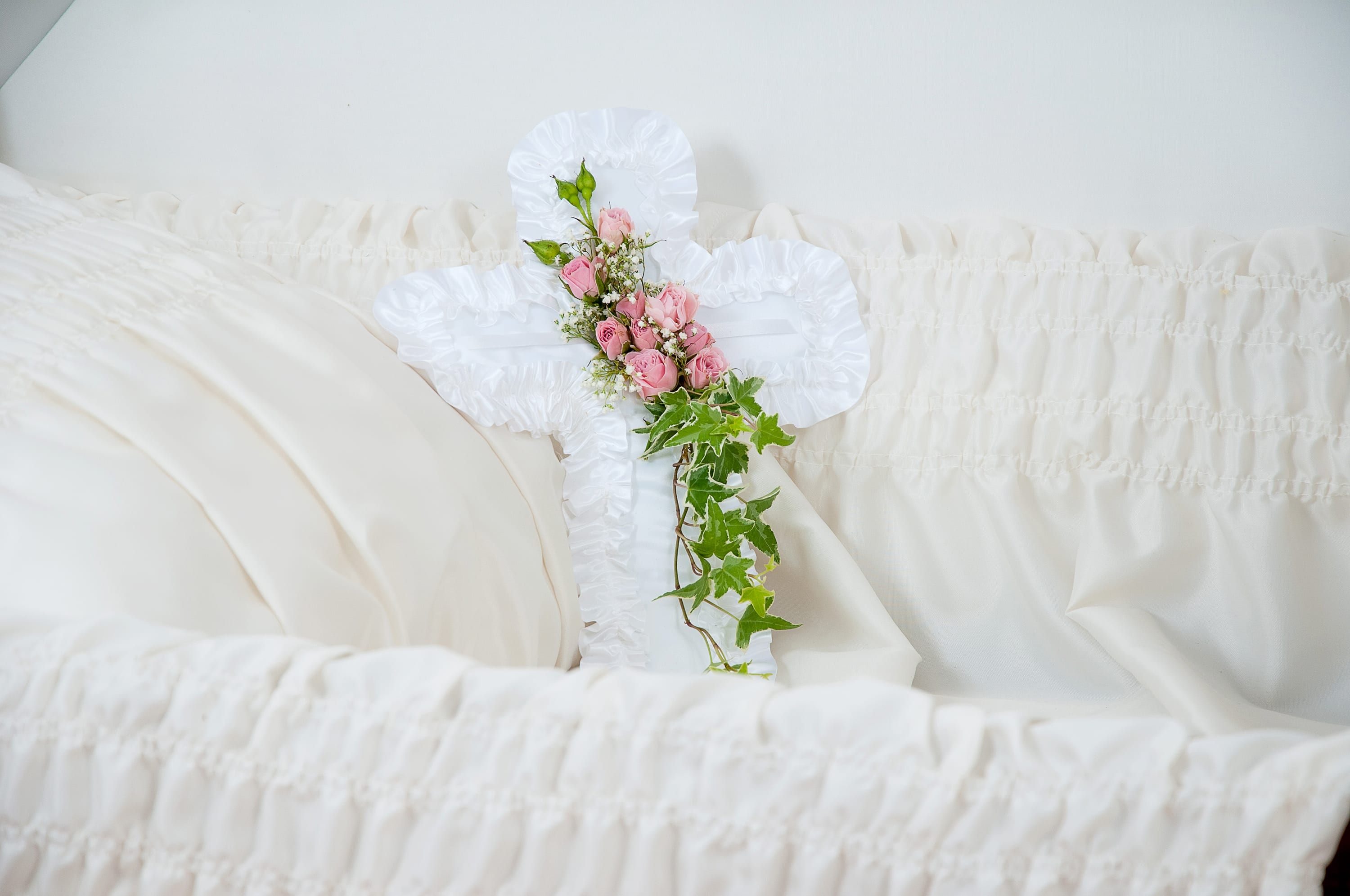 White casket spray with pink roses and ivy
