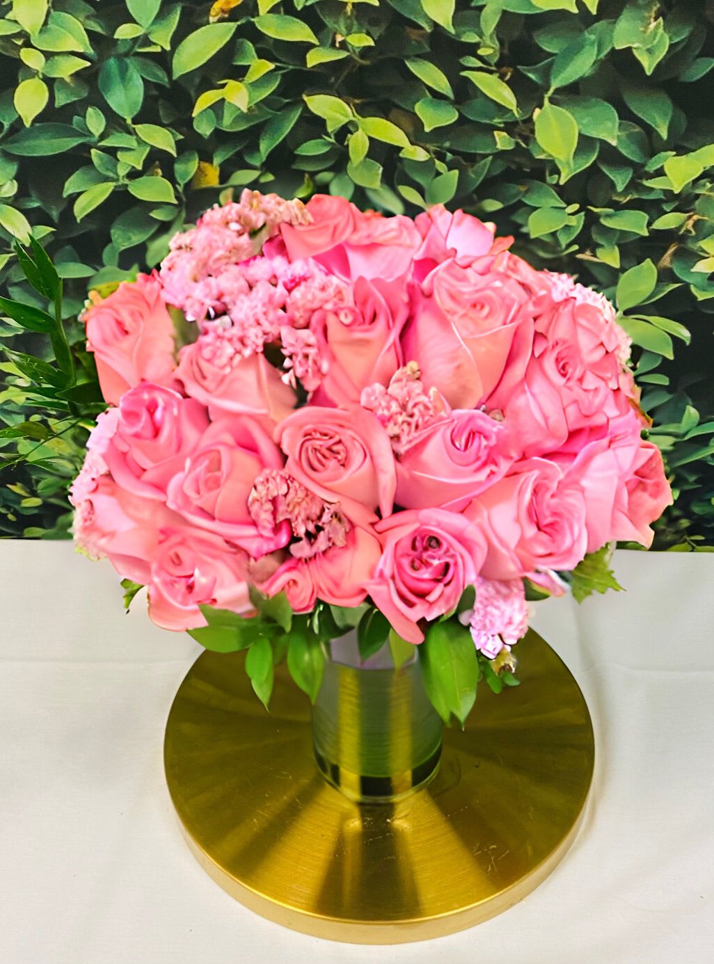 Pink rose bouquet in a gold vase on a round gold base