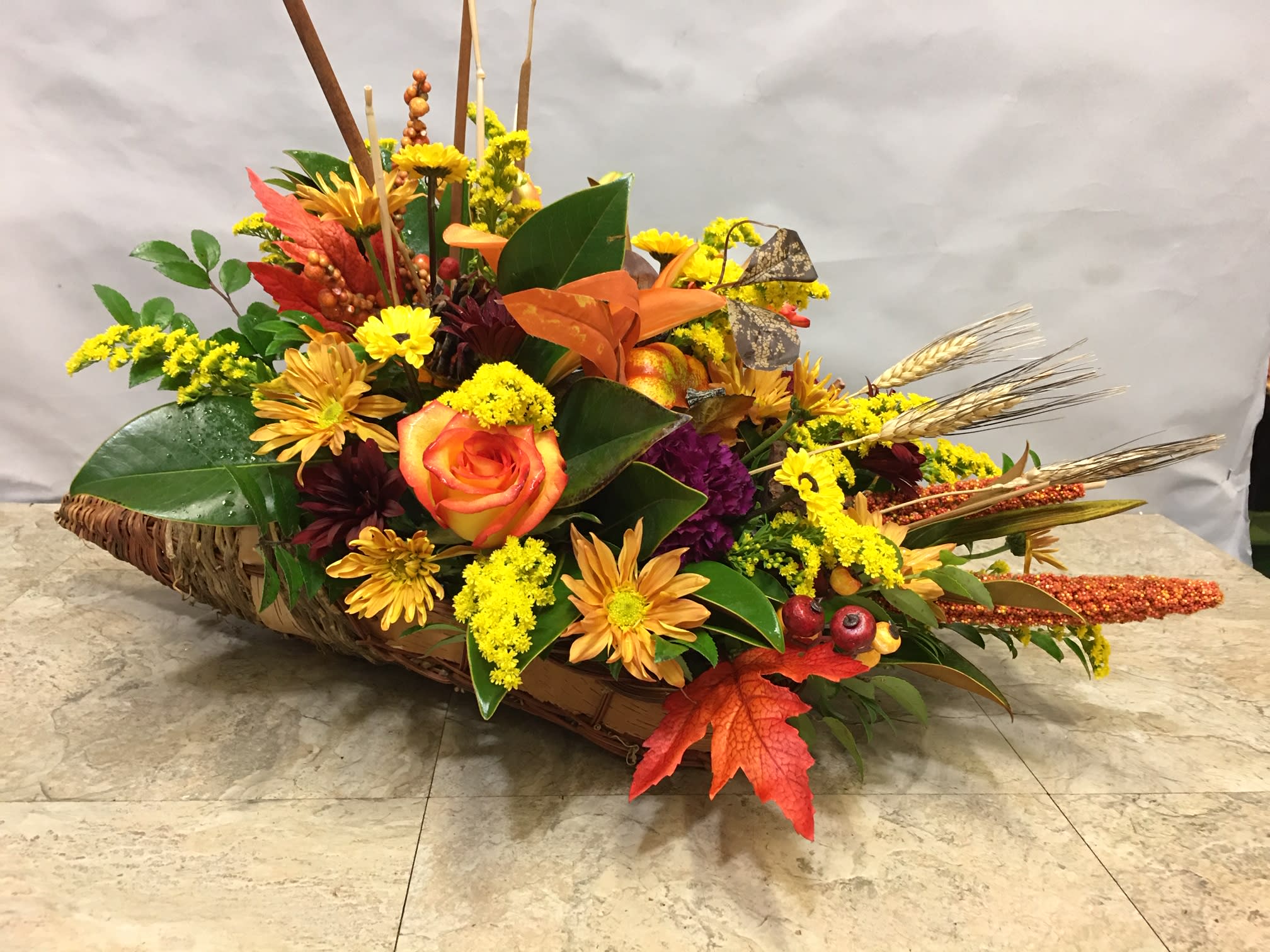 Autumn floral arrangement in a woven basket with orange roses and yellow blooms