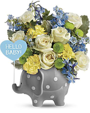 Bouquet of white roses, blue flowers, and yellow carnations in a gray elephant container