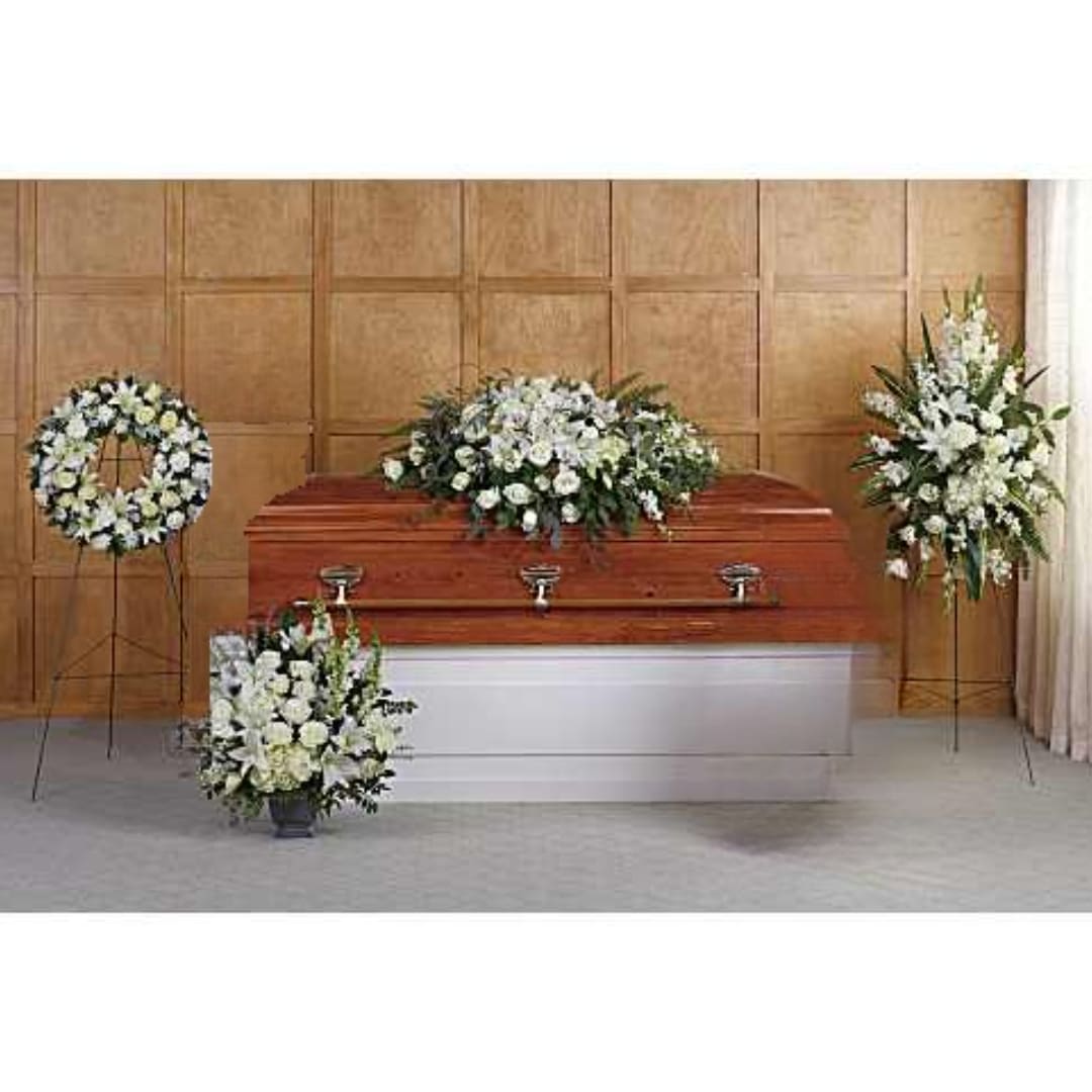 White funeral flowers arranged around a casket in a chapel
