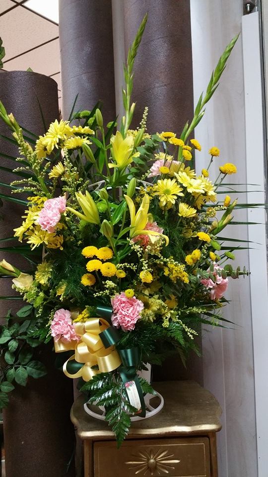 Large yellow and pink floral standing arrangement with ribbon
