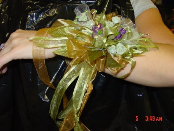 Gold ribbon wrist corsage with small purple and white flowers