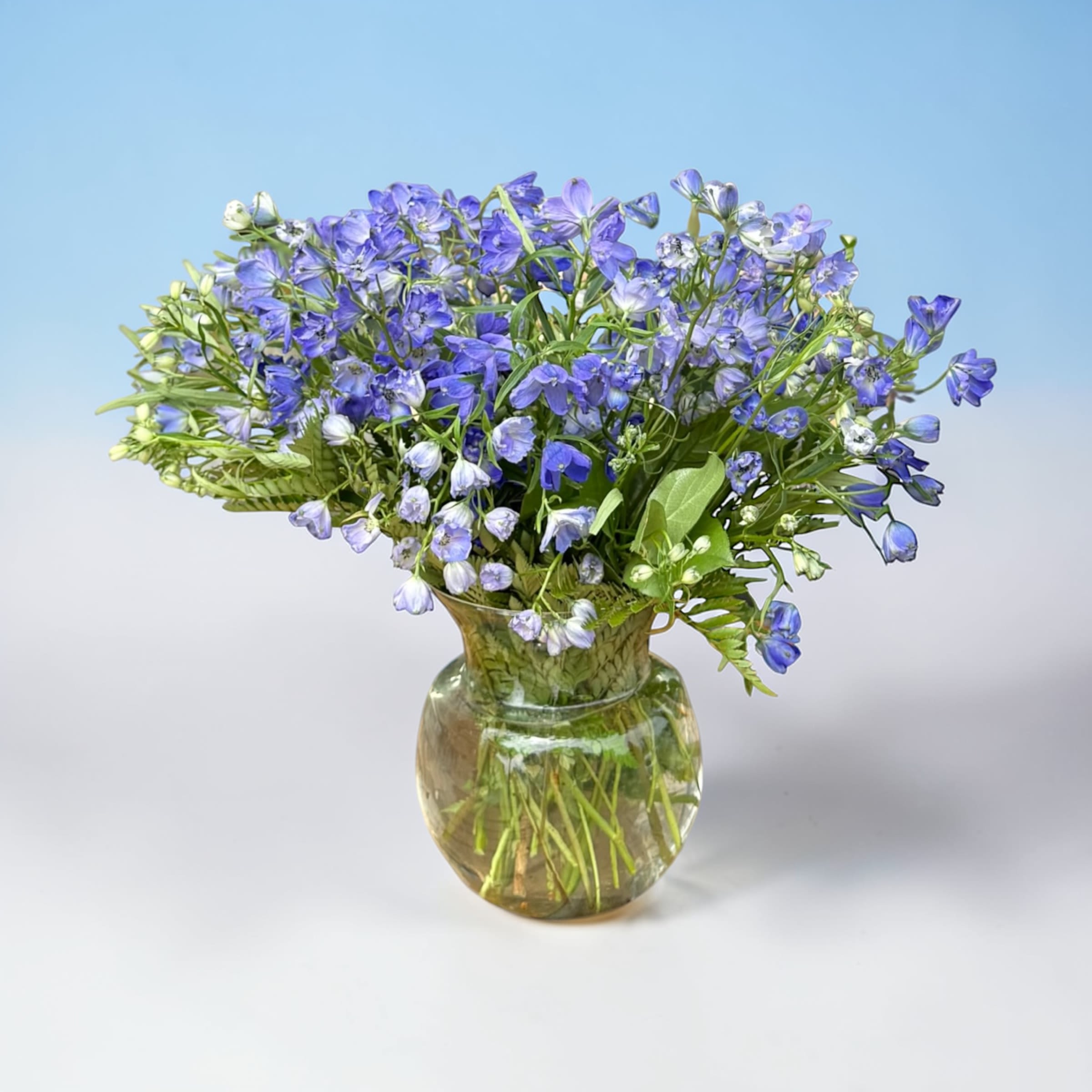 Blue-purple flowers arranged in a clear glass vase