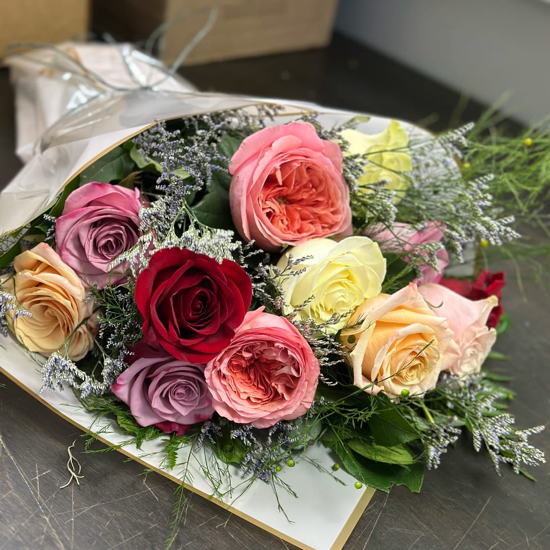 Mixed bouquet of roses in pink, red, and cream tones with delicate filler flowers
