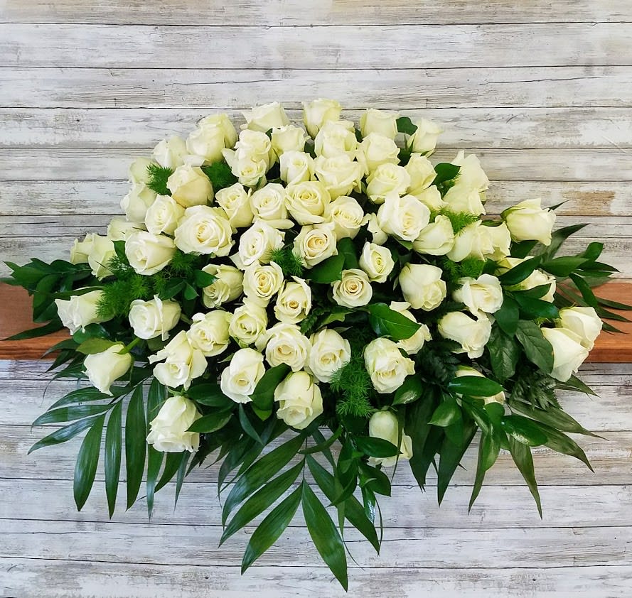 Large bouquet of white roses with green foliage on a wooden surface