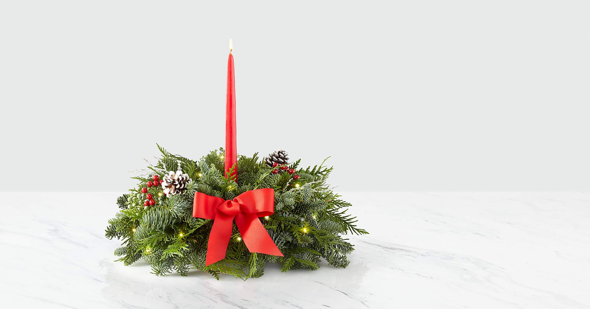 Holiday centerpiece with a red taper candle and evergreen wreath