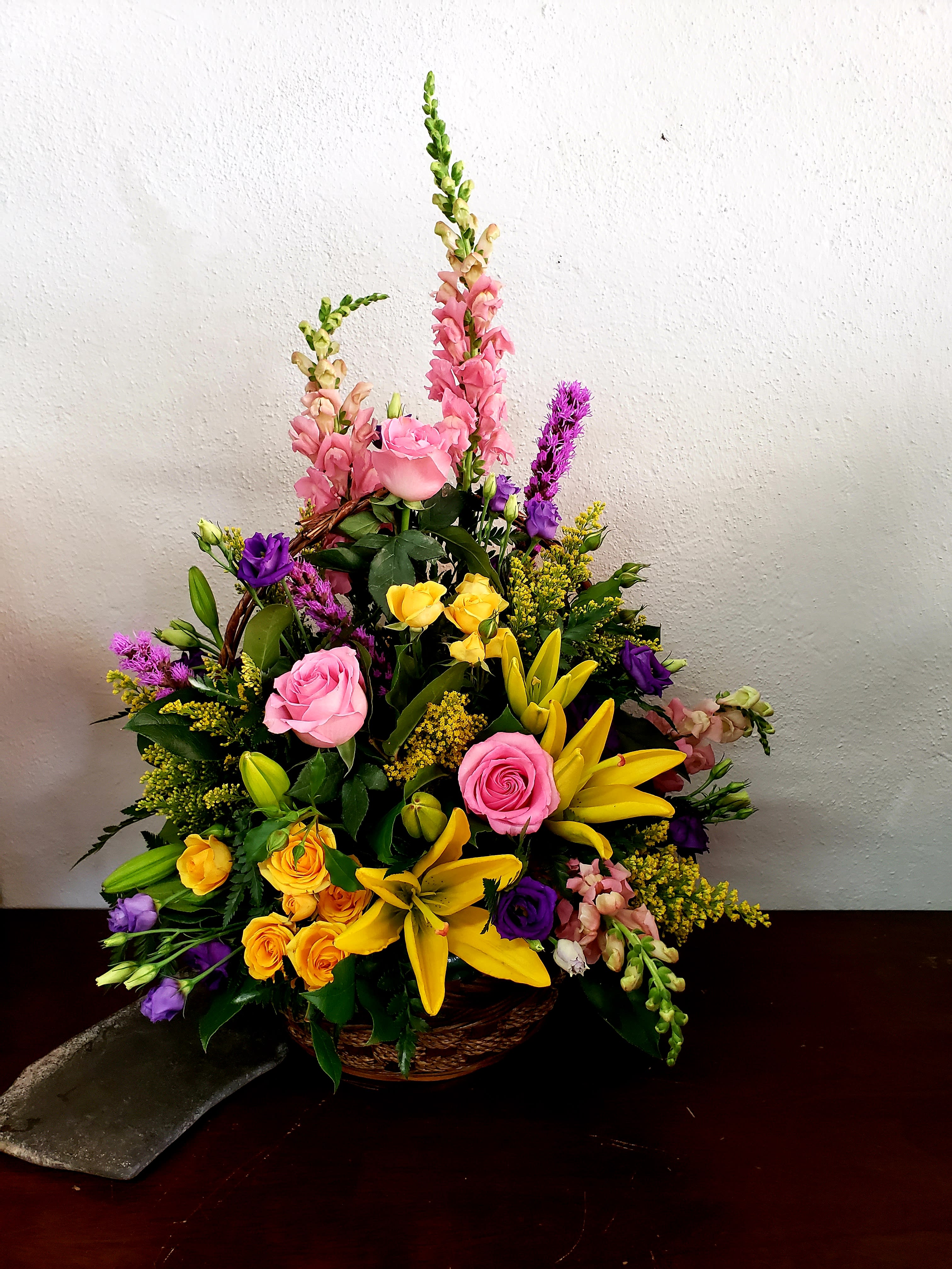 Mixed bouquet of pink, yellow, and purple flowers in a basket