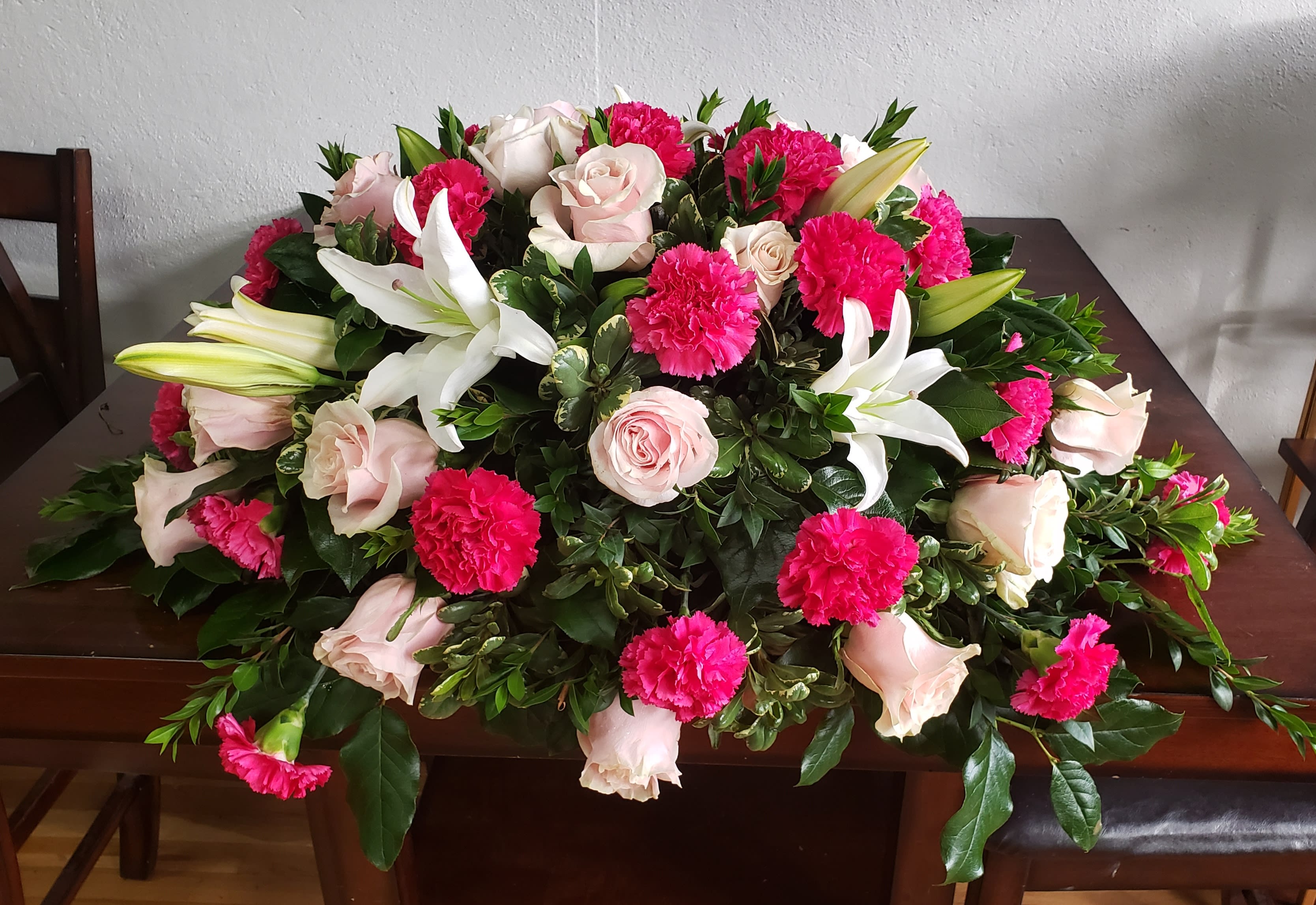 Large floral casket spray with pink roses, white lilies, and hot pink carnations