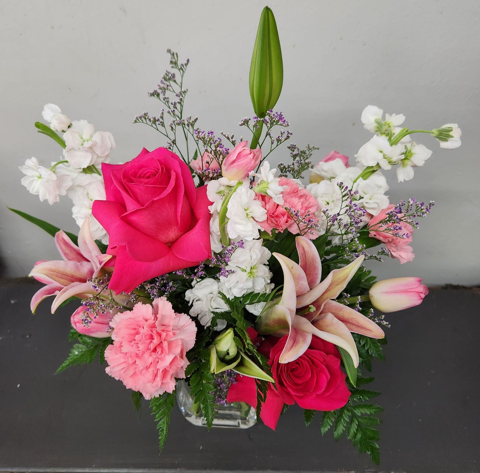 Raspberry Bowl - We start with fresh roses and lots of flowers with fragrance. Designed in assorted vases for just a little different look each time. Each design is unique. Seasonal flowers used so selection may vary.