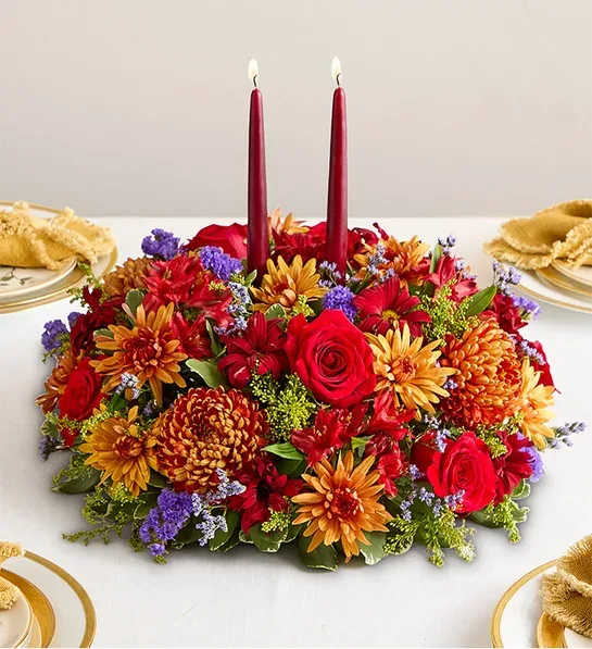 Briliant Autumn - Set the table in brilliant style. This centerpiece captures the rich beauty of autumn, with bursts of red, bronze, and purple amid assorted greenery. A burgundy taper candle stands at the center, ensuring a warm and welcoming ambience for every gathering.