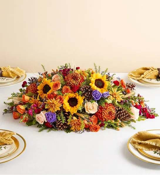 Crisp Fall - This vibrant centerpiece transforms any table into the setting for a harvest celebration. Sunflowers, roses, lisianthuses, and more blooms in a dazzling array of autumnal colors make this a memorable addition to any gathering.