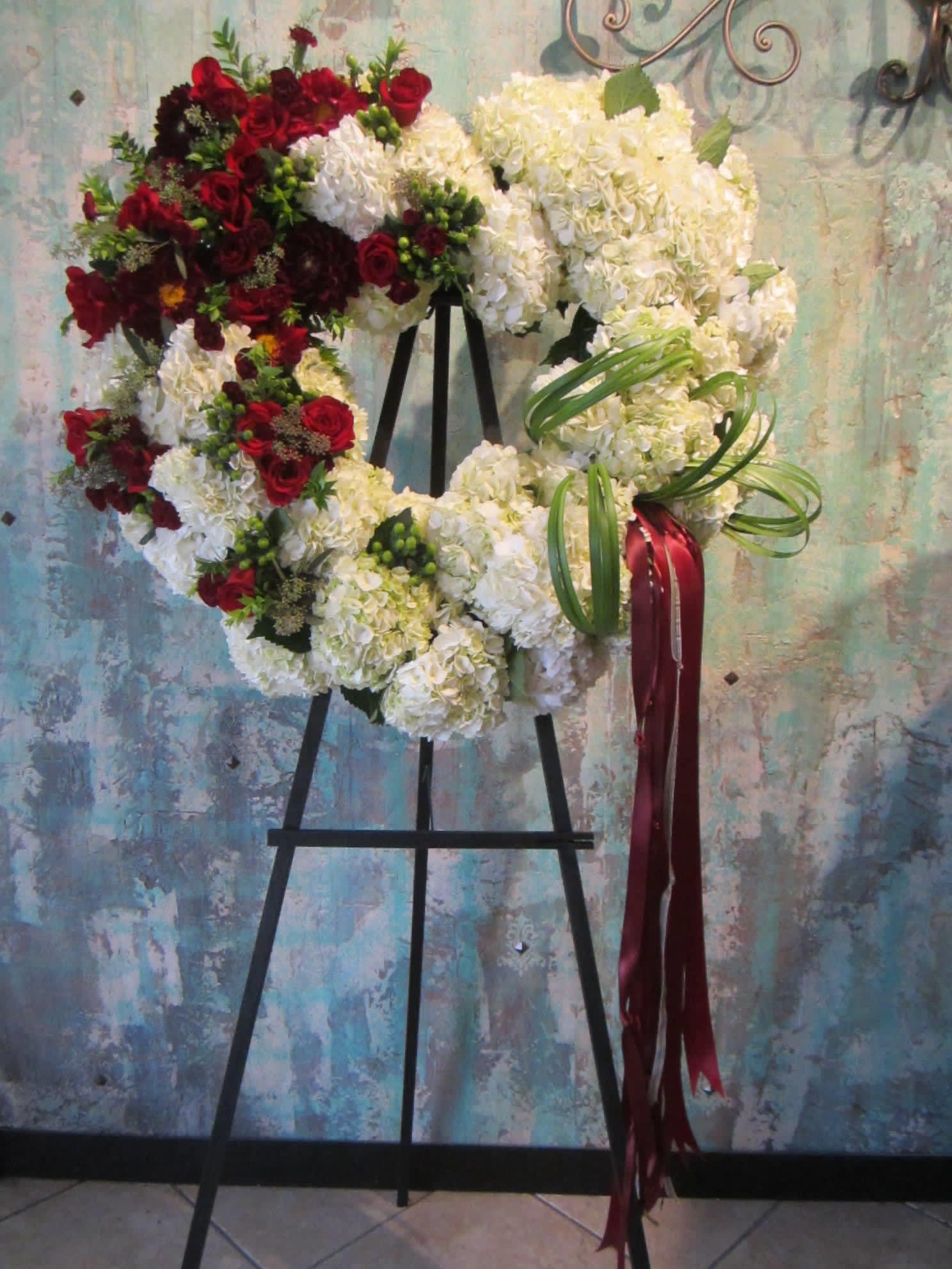 Heart-shaped floral wreath with red and white flowers on an easel