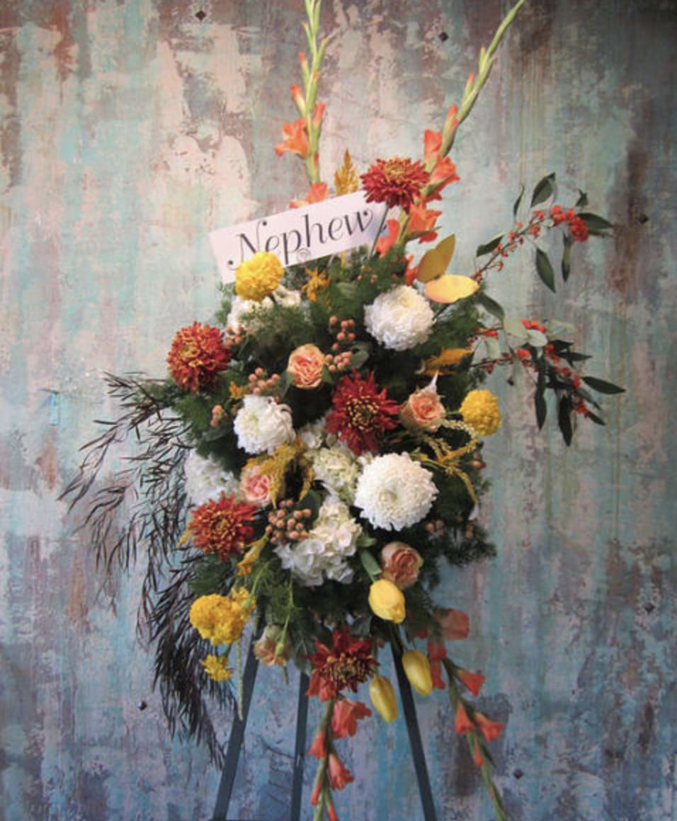 Standing floral spray with orange, yellow, white, and red blooms