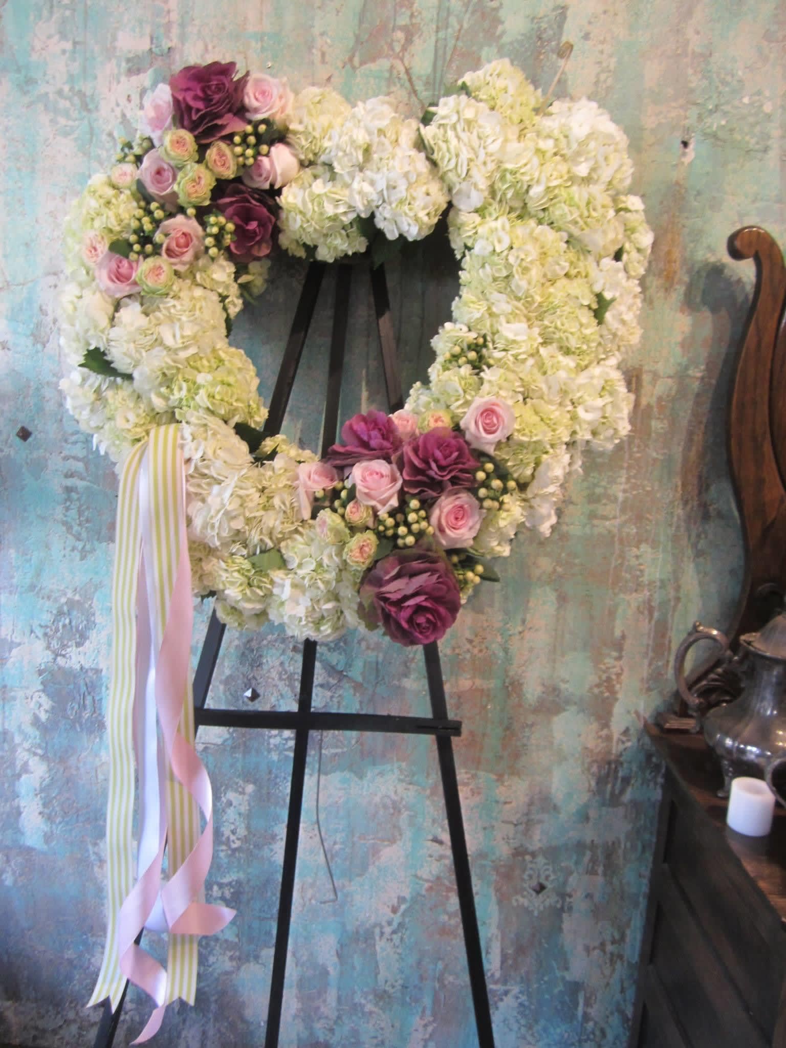 Heart-shaped floral wreath on an easel with pink and white flowers