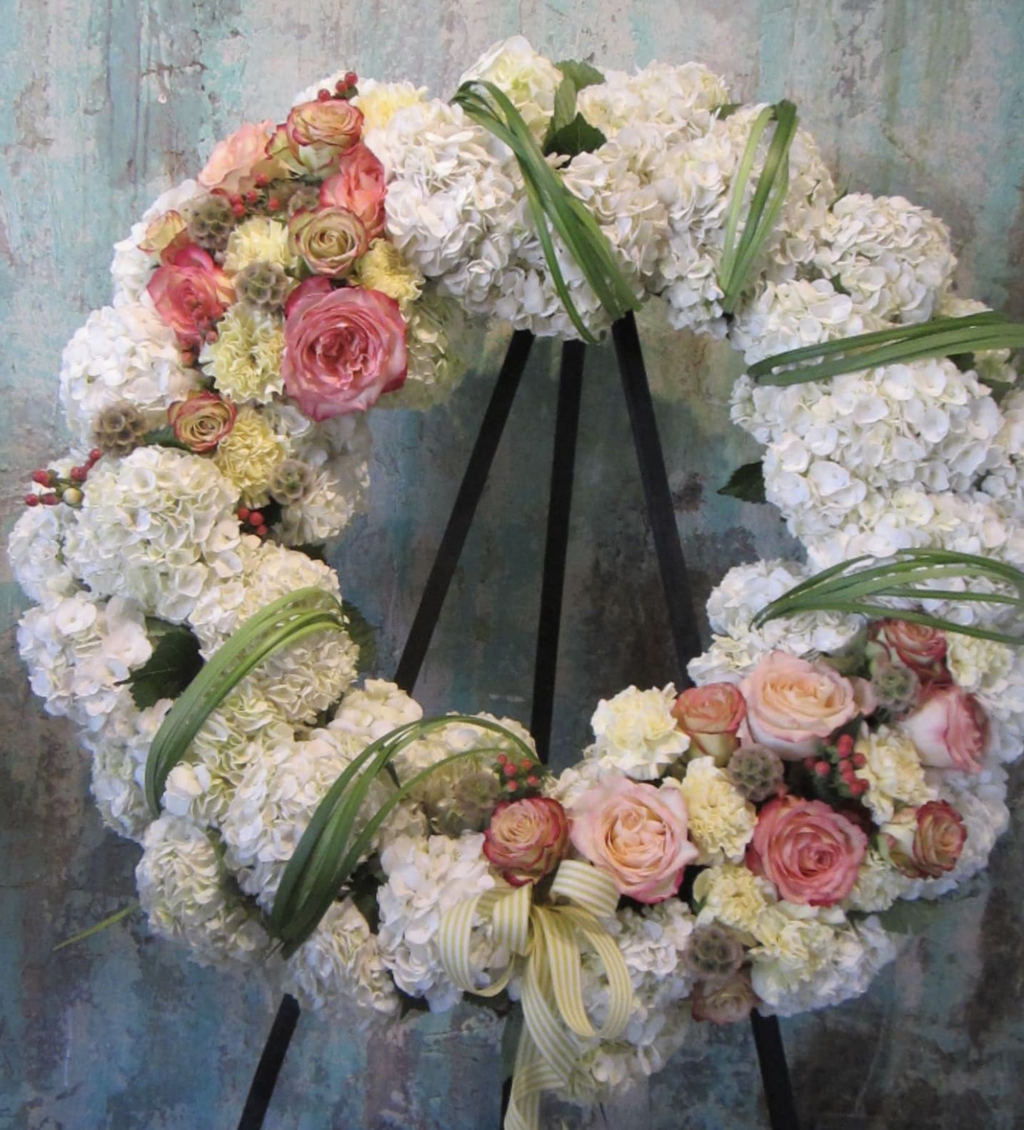 Floral wreath of white hydrangeas and pink roses on a black stand