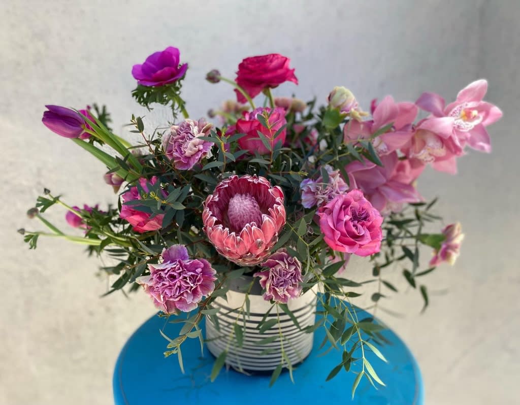 Pink and purple mixed bouquet in a striped container