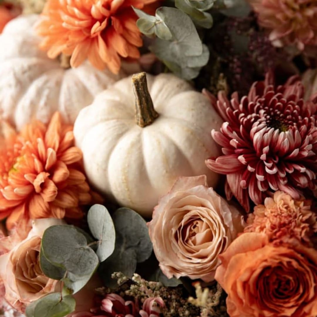 Autumn floral arrangement with white pumpkins, orange and blush blooms