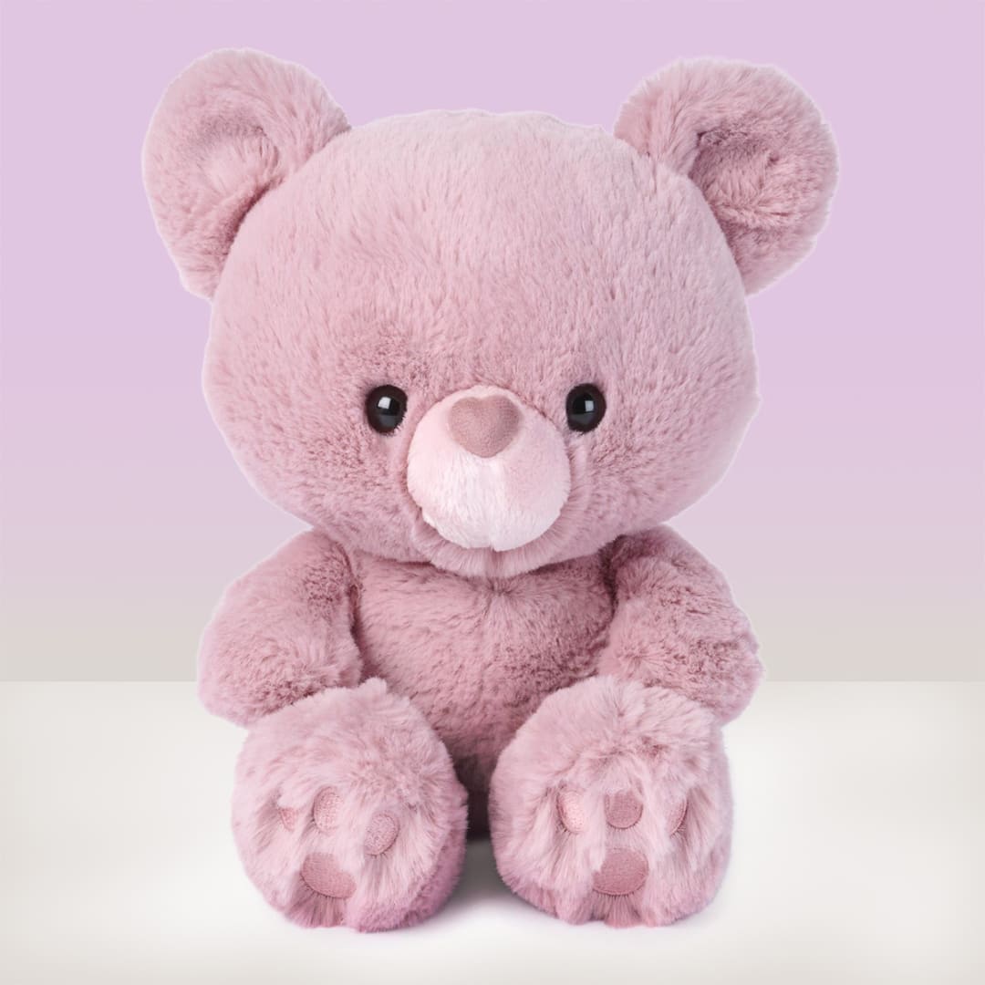 Pink plush teddy bear sitting against a pastel background