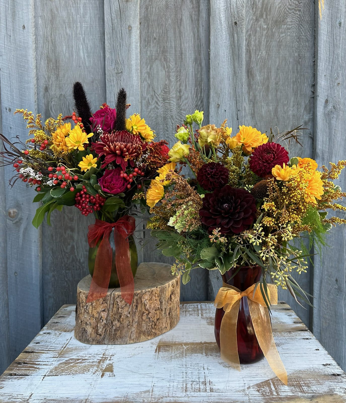 Two autumn flower arrangements in glass vases with ribbon bows