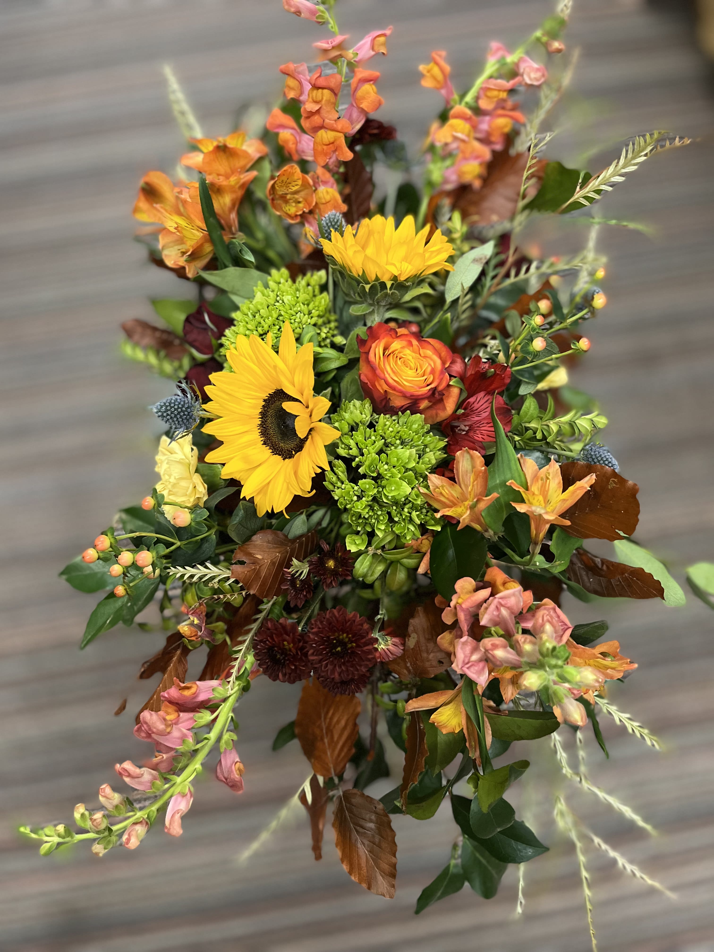 Mixed bouquet with sunflowers, orange blooms, and pink snapdragons