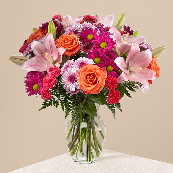 Pink lilies and orange roses in a clear glass vase