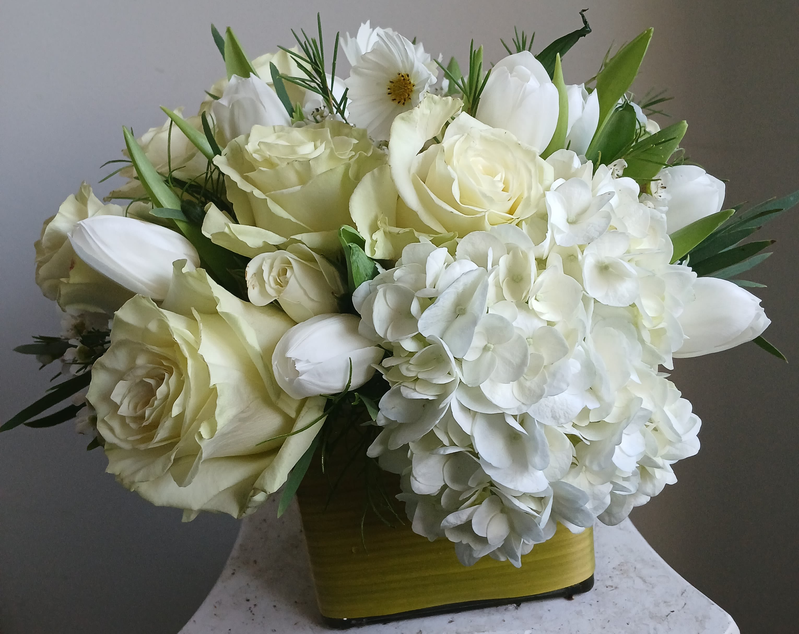 White roses and hydrangeas arranged in a yellow vase