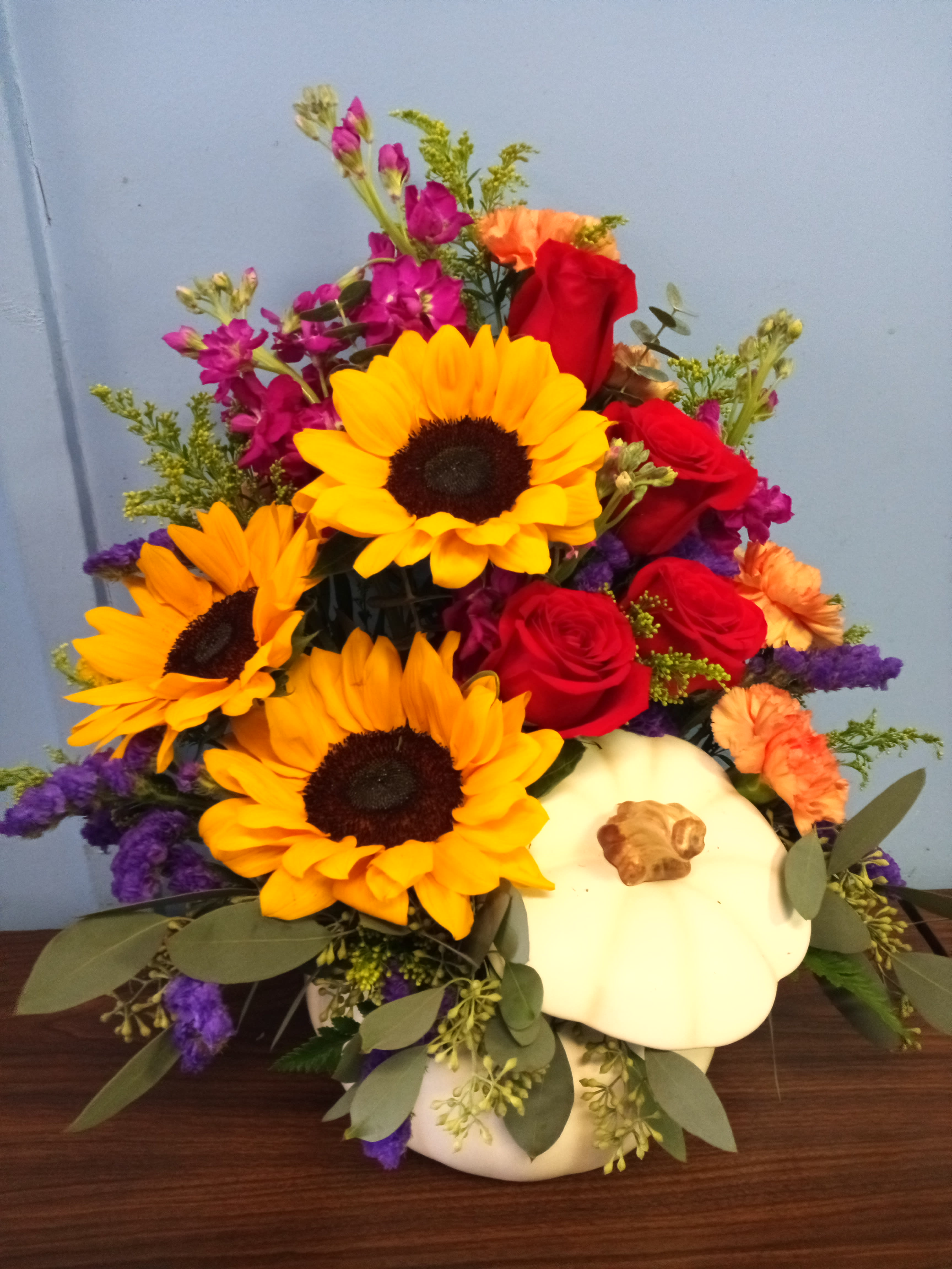 Mixed bouquet with sunflowers, red roses, and a white pumpkin container
