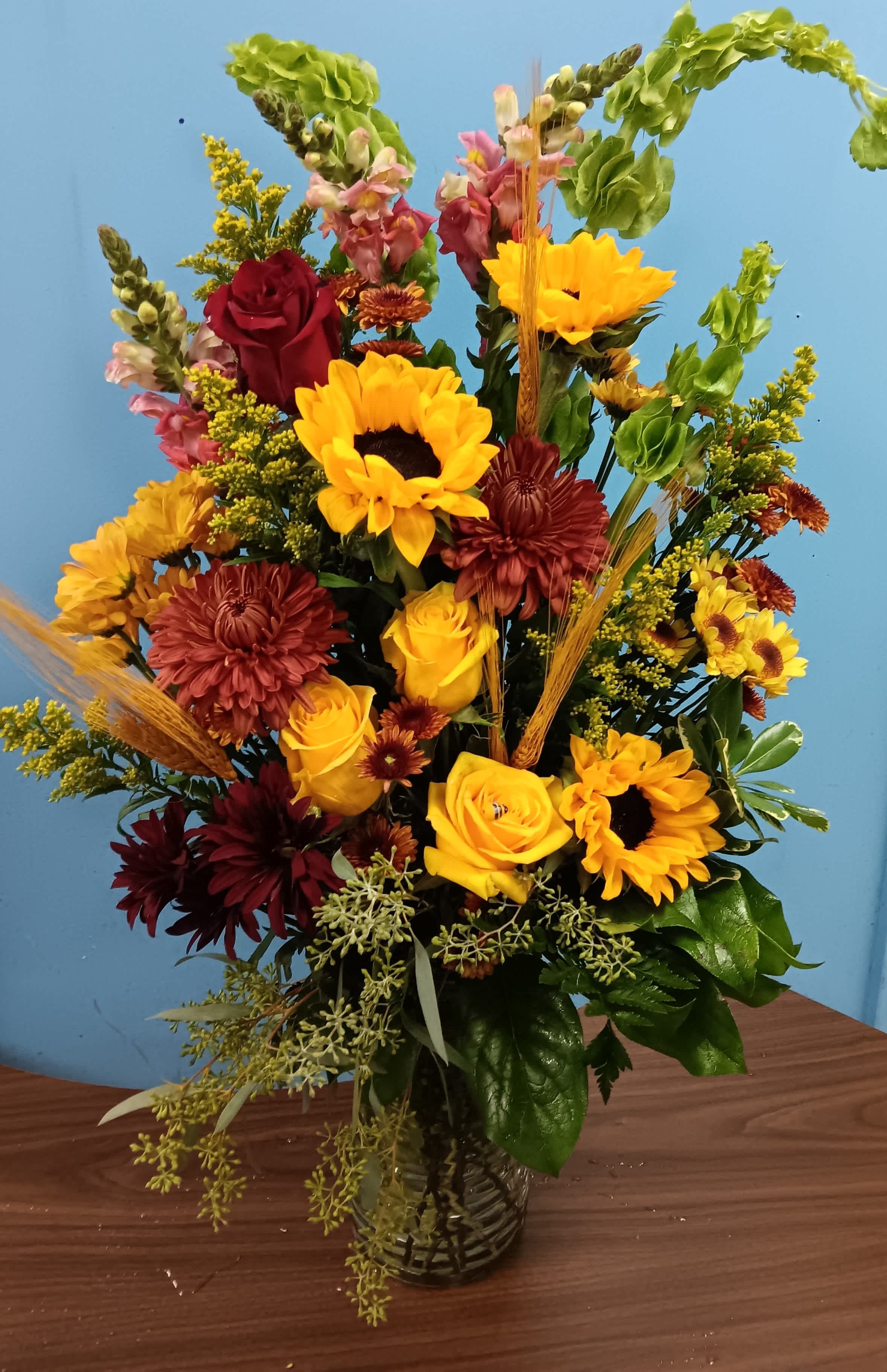 Mixed bouquet of sunflowers, roses, and chrysanthemums in a glass vase