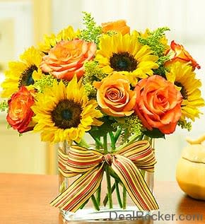 Sunflowers and orange roses in a glass vase with a striped ribbon