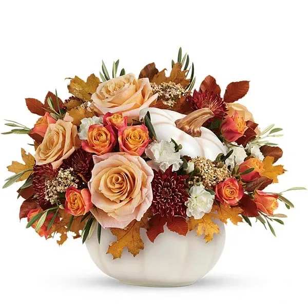 Autumn floral arrangement in a white vase with peach and orange roses