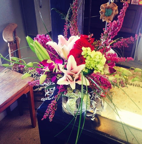 Mixed bouquet with red roses, white lilies, and pink orchids in a vase