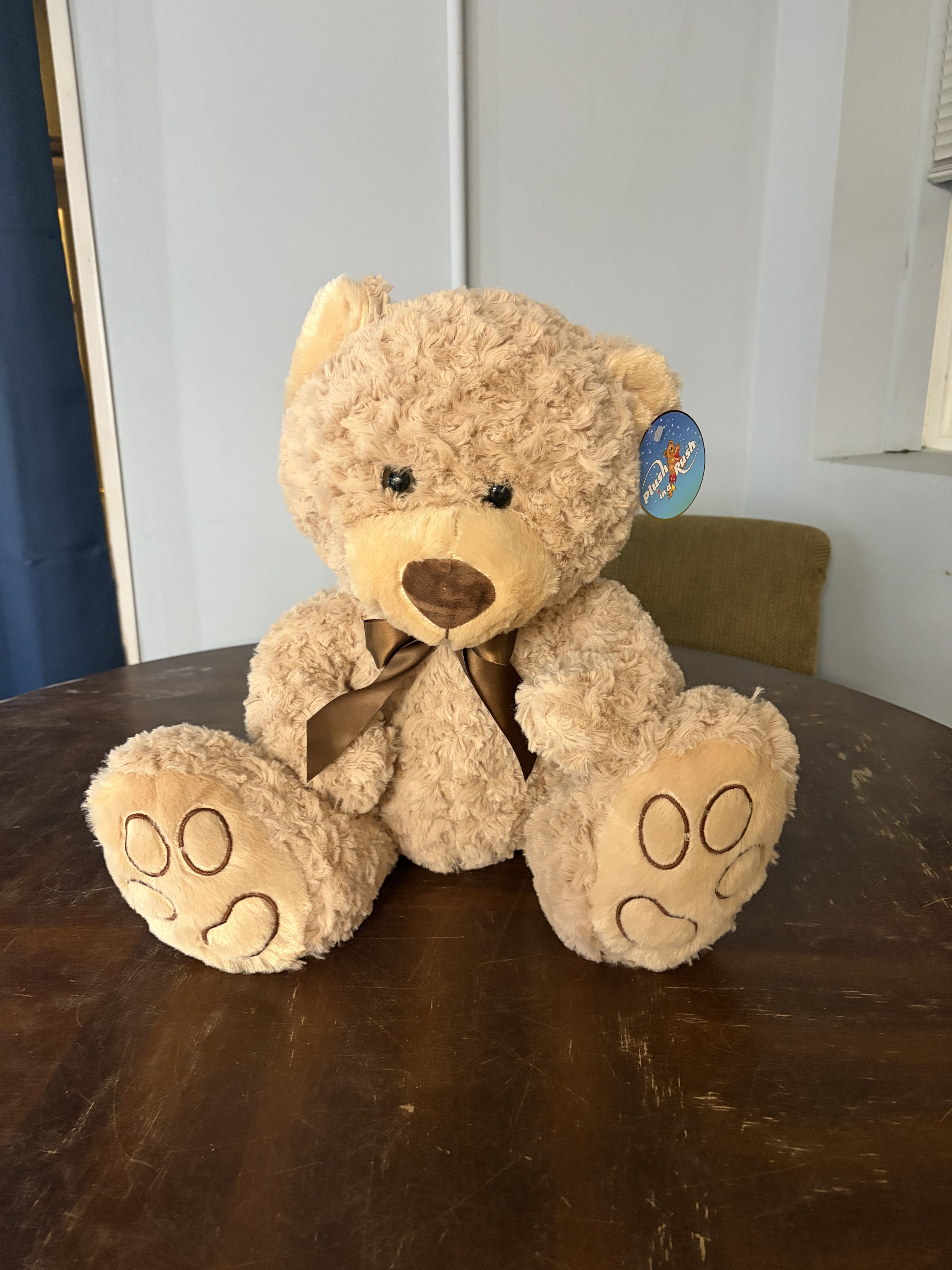 Plush teddy bear with a brown ribbon sitting on a table