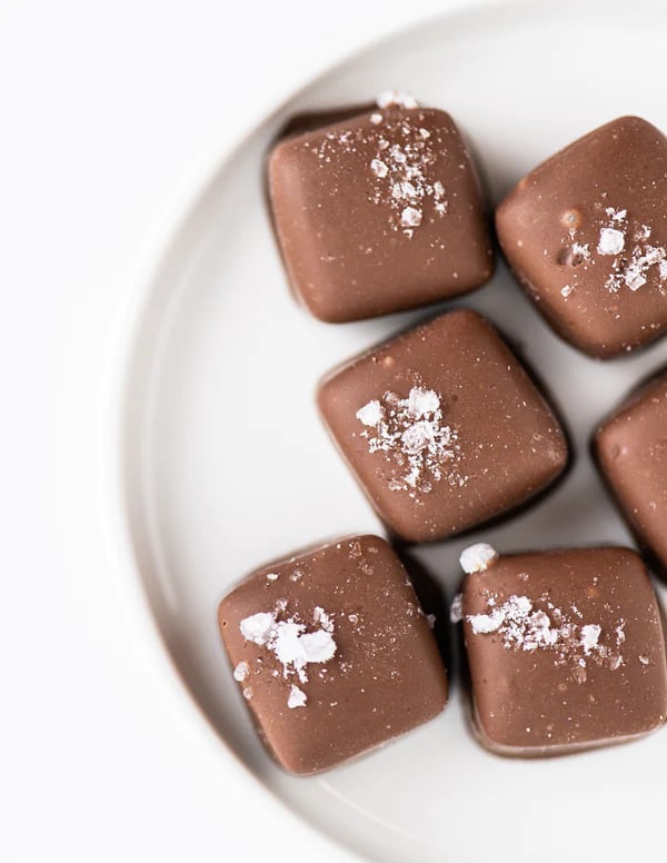 Six square milk chocolates sprinkled with coarse salt on a white plate