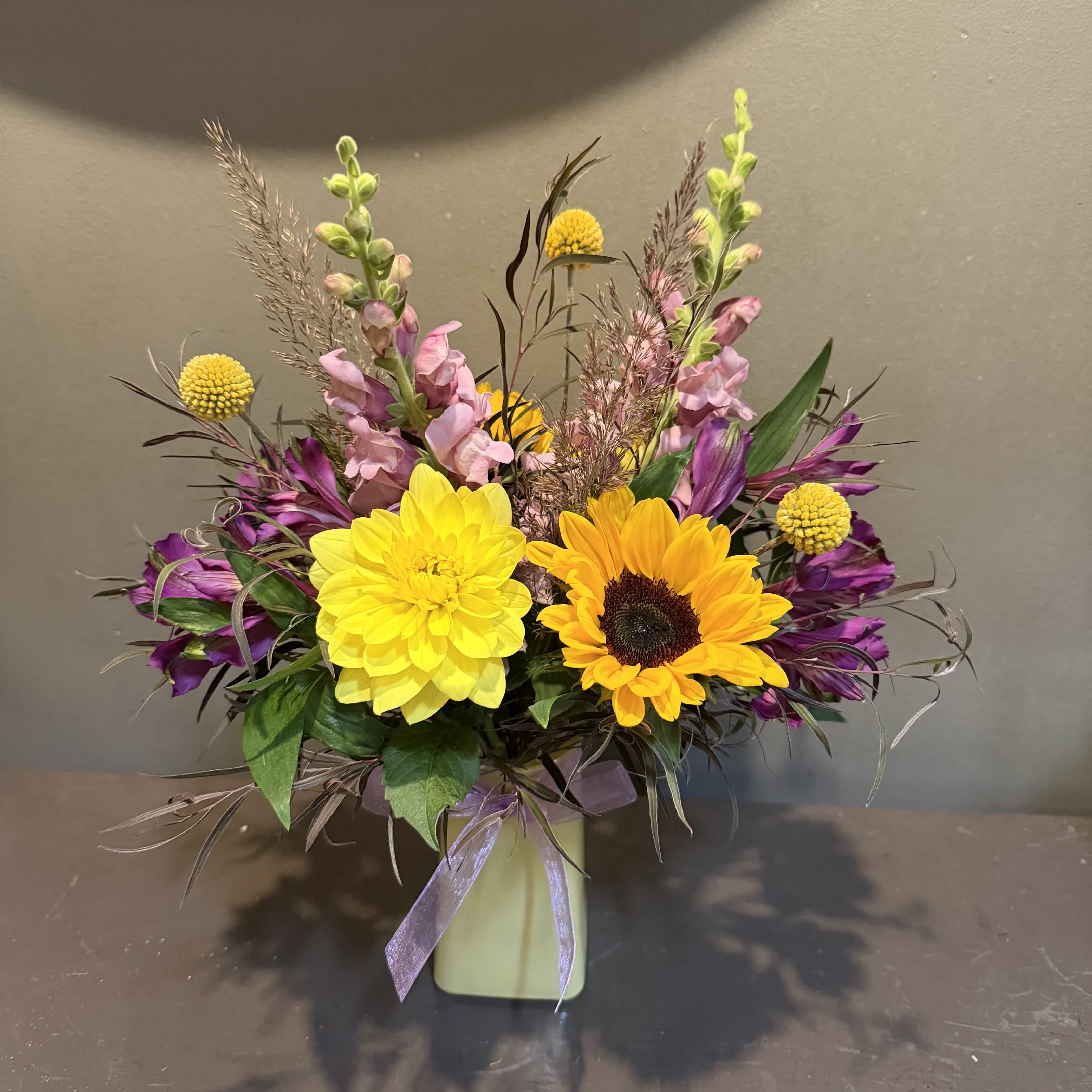 Colorful bouquet with yellow and orange blooms in a pale vase