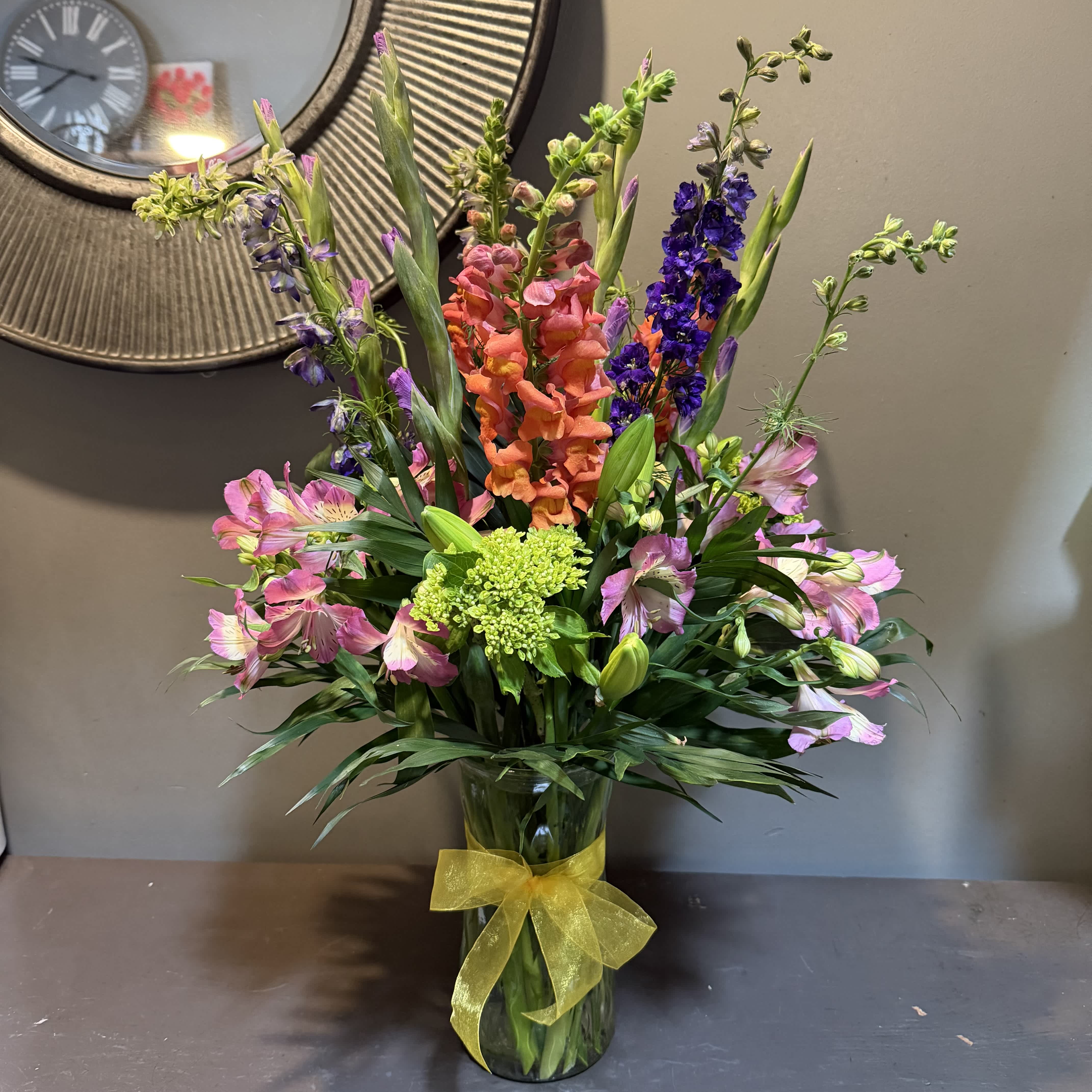 Colorful mixed bouquet in a glass vase with a yellow ribbon