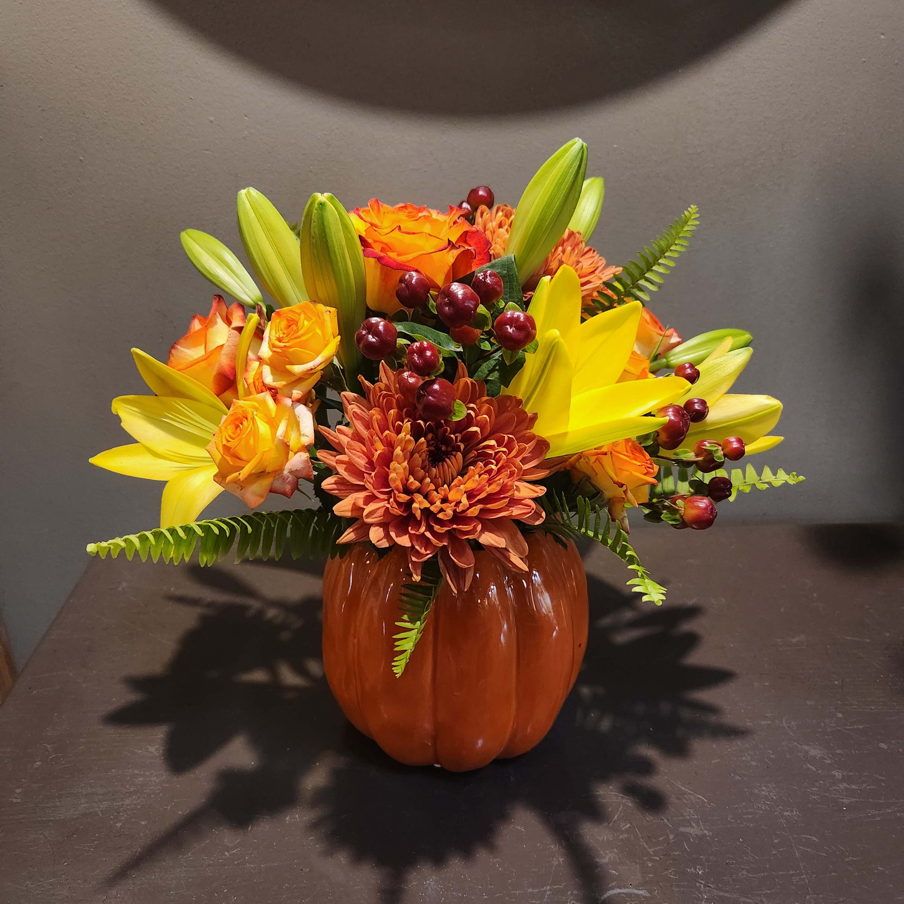 Orange and yellow floral arrangement in a pumpkin-shaped vase